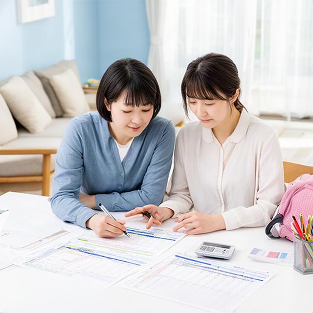 つくば市の明るいリビングで子どもの学校予定と家計表を確認する両親